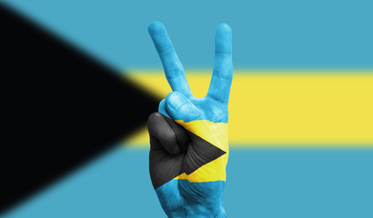 bahamas national flag painted onto a male hand showing a victory, peace, strength sign