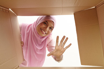 woman opening a carton box and looking inside, relocation and unpacking concept