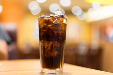 Cool ice soft drink cola carbonated liquid fresh food with soda water, white dish on wooden table with handsome man sitting  brown sofa in pizzeria restaurant.