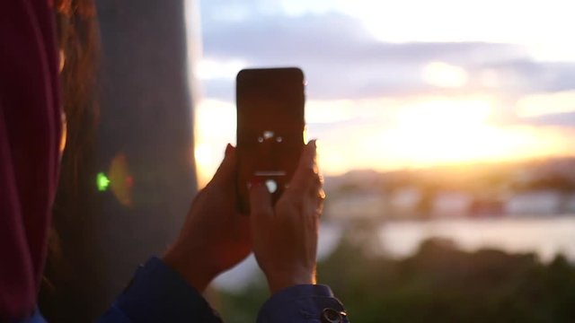 Make a photo on the phone of a beautiful sunset in the city near the river. slow motion, 1920x1080, full hd