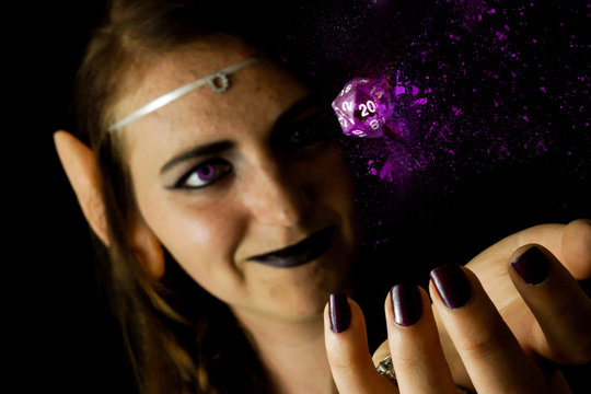 Young female dressed as an elf with a polyhedral die