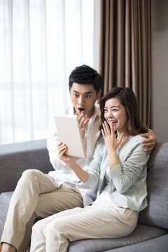 Cheerful young couple using digital tablet at home