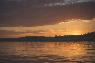 Summer sunset on the Oka river, with a flying paraglider