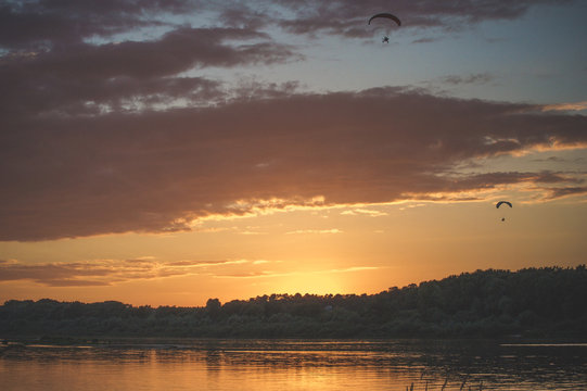 Summer sunset on the Oka river, with a flying paraglider