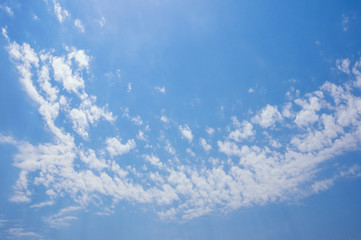 Naklejka na ściany i meble Blue sky with many small white clouds forming a curved strip