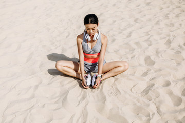 sportswoman stretching on sand
