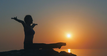 Girl practices yoga near the ocean