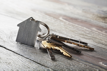 estate concept, keychain with house symbol, key on wooden background
