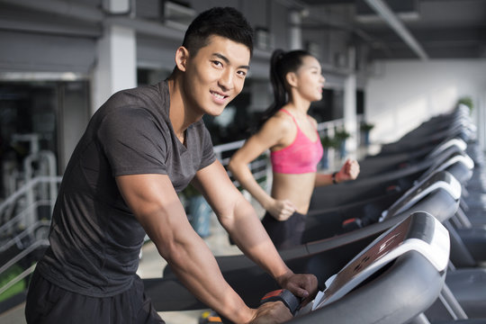 Young couple exercising on treadmills in gym