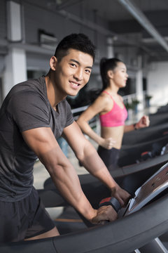 Young couple exercising on treadmills in gym
