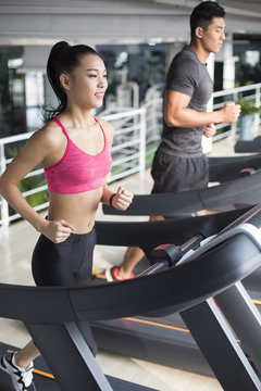 Young couple running on treadmills in gym