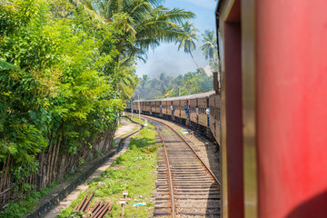 Fototapeta na wymiar In the railroad car on the way to Colombo. Locals stand in the doors of the rail wagon. The coastal line is a major railway line in Sri Lanka. A popular means of transport on the island