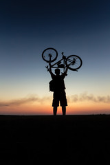 silhouette with the bike / the man with the bike in the hands of the sunset