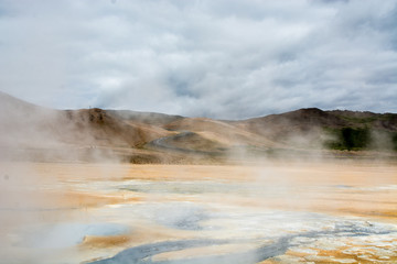 Mudpot in the Namafjall geothermal area, Iceland - area around boiling mud is multicolored and cracked