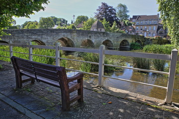 The Old Town Bridge on the river Avon with a wooden bench in the foreground, Bradford on Avon, UK