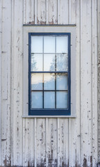 Obraz na płótnie Canvas blue window on side of old faded white barn