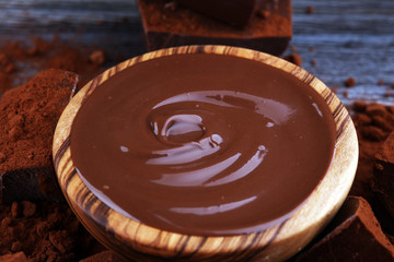 Chocolate cream melted, chocolate pieces and chocolate powder on wooden table