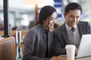Happy business people working on laptop at the airport