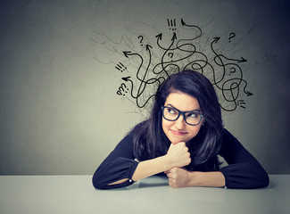 Business woman thinking contemplating a solution sitting at table