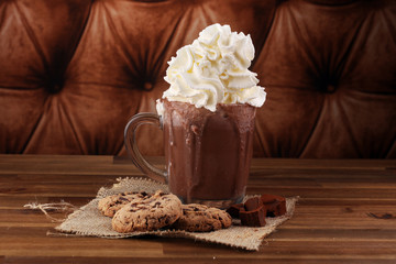 A messy cup with hot chocolate and chocolate chip cookies.
