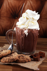 A messy cup with hot chocolate and chocolate chip cookies.