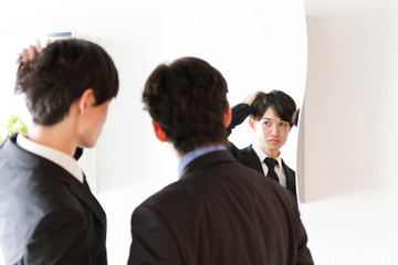 同僚と鏡で身だしなみをチェックする若い日本人ビジネスマン