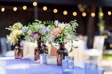 Flower table decorations for holidays and wedding dinner. Table set for holiday, event, party or wedding reception in outdoor restaurant.