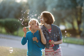 Portrait of funny lovely little girls blowing soap bubbles