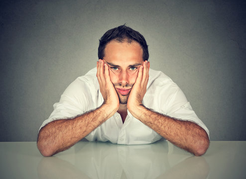 Sad bored man sitting at table in his office