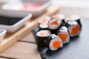 Sushi rolls with salmon and dishes with soy sauce and ginger 