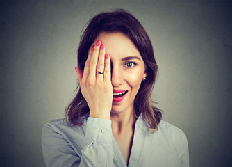 Young surprised woman hiding half face with her hand