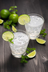 Fresh cocktail with lime, ice and mint on a rustic background. Copy space, top view