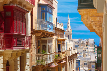 The traditional Maltese colorful wooden balconies and St. Paul's Anglican Pro-Cathedral in Valletta, Malta - obrazy, fototapety, plakaty