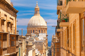 The traditional Maltese colorful wooden balconies and Our Lady of Mount Carmel in Valletta, Malta