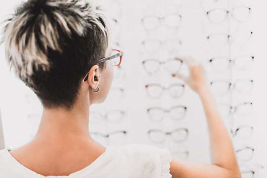 Beautiful Middle Age Woman Choosing A Glasses In Optician Store.