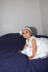 little cute girl in parents bed with lovely white dress for party