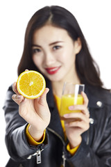 asian woman showing a half of an orange and a glass of orange juice
