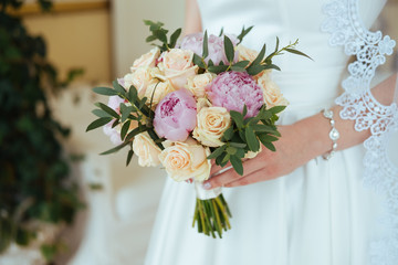 Colorful peony and roses bouquet in bride's hands