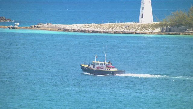 Pilot Boat in Nassau Bahamas Exiting the Port Sailing on Tropical Blue Water Past the Iconic Lighthouse on a Sunny Day in the Bahamian Capital