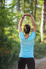 Young female model stretching in the woods