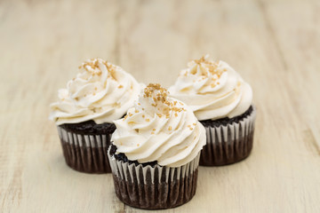 Chocolate Cupcakes With White Icing and Gold Sprinkles