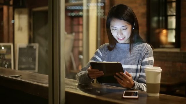 Young woman using tablet pc at coffee shop at night