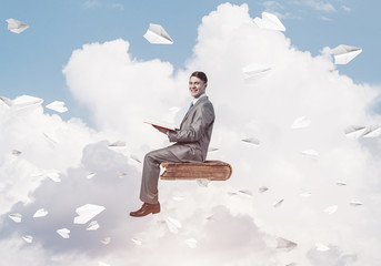 Businessman or student reading book and paper planes flying arou