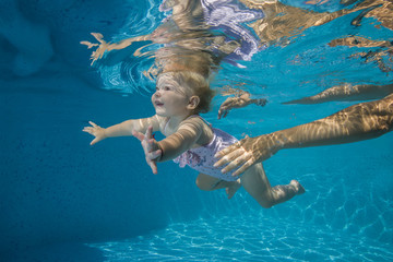 little child learns to swim underwater in the pool