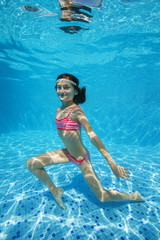 Teen girl posing under water in the pool