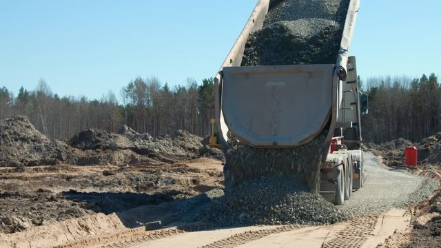 Dump truck delivering gravel to the road construction site in new suburb development