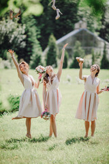 Naklejka premium Beautiful bridesmaids in short dresses through their shoes up standing on the lawn