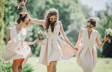 Elegant bridesmaids walk on the green lawn