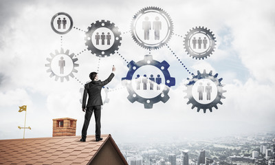 Businessman on house roof presenting teamwork and connection con