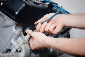 A close-up of an auto mechanic smiling repairs the engine of a lorry or bus replacement of a candle, a concept repair in a garage, a workshop.